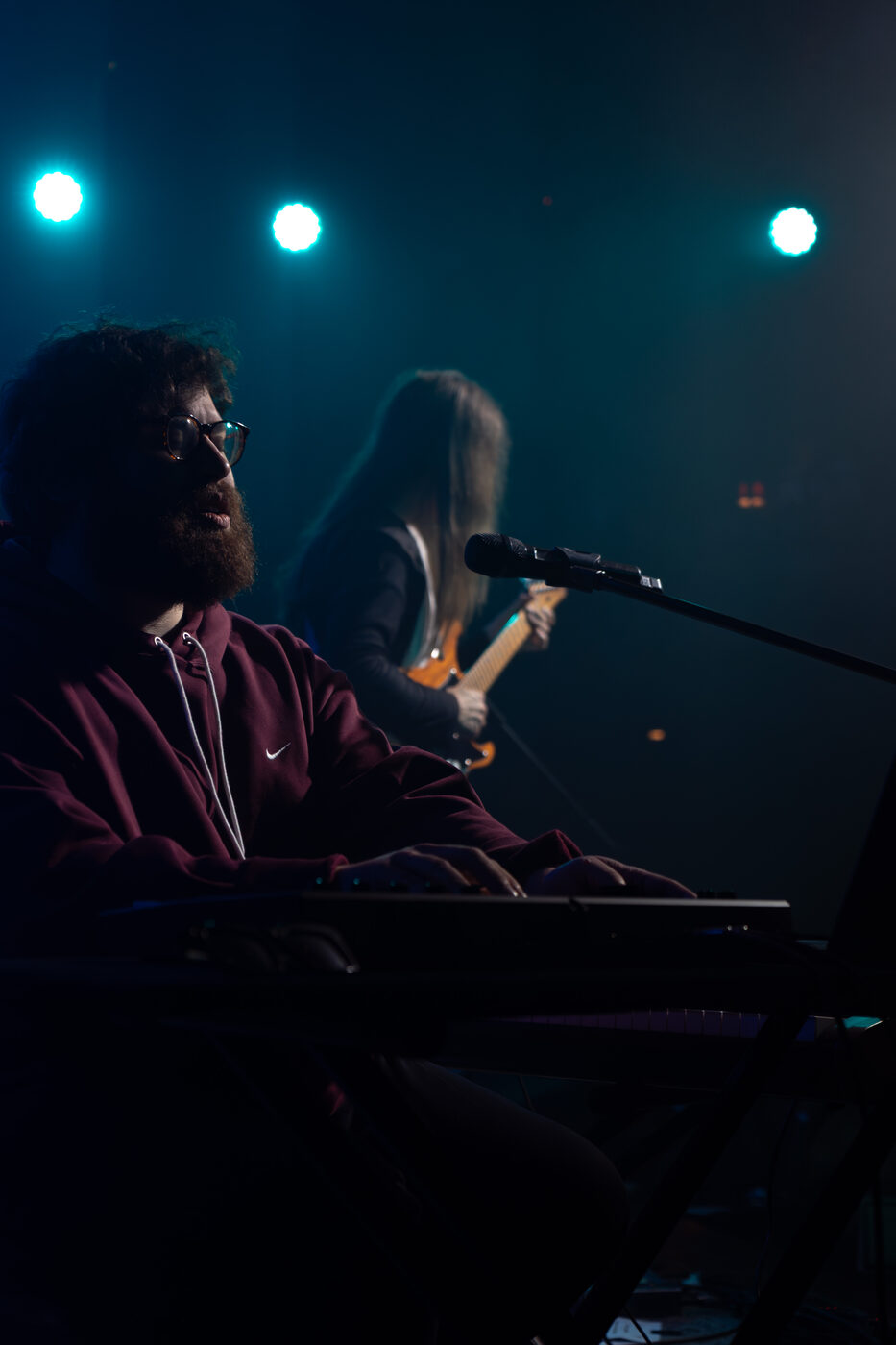Rob Araujo playing keys in teal stage light